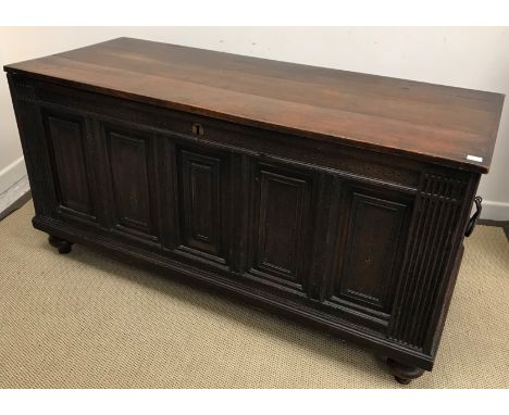 A 17th Century and later oak coffer, the replacement top over a five panel front, flanked by fluted stiles and fielded panel 