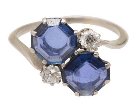 A sapphire and diamond cross-over ring the two octagonal step-cut sapphires obliquely-set with a brilliant-cut diamond to eit