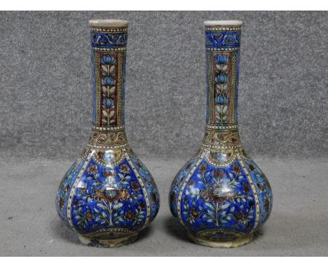 A pair of handpainted ceramic vases with a stylised floral and foliate design in blues, greens and purples. H.34cm