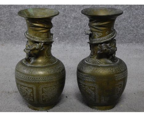 A pair of brass Chinese vases with engraved design depicting clouds, flowers, lucky bats and butterflies and a sculpted drago