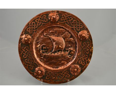 A possibly Scottish arts and crafts copper plaque, decorated with a galley and a Celtic border. Diameter 29cm.
