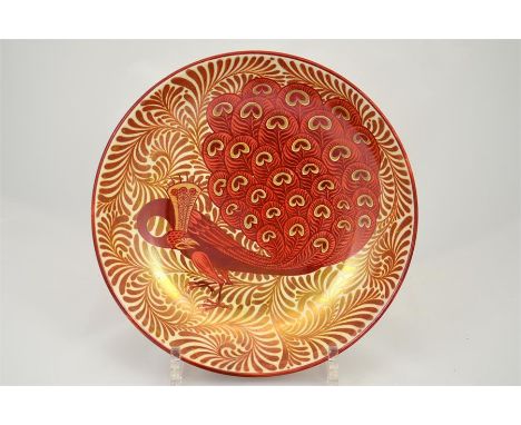 A William de Morgan shallow dish by Charles Passenger, decorated with a peacock in a ruby and copper lustre. Painted concentr