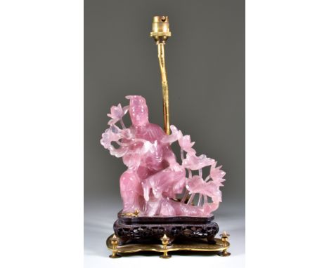 A Chinese Pink Agate Carved Figure of the Seated Guanyin, on pierced wood base, mounted with gilt metal electric lamp fitting