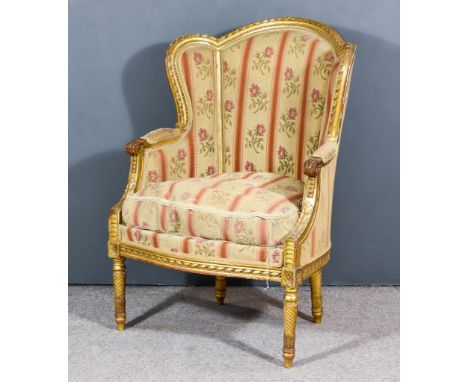 A French Gilt Framed Wing Back Fauteuil of Louis XV Design, the shaped and moulded frame with ribbon and bead ornament, uphol