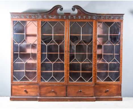 A 19th Century Mahogany Break Front Bookcase, the cornice with scroll moulded pediment, the frieze applied with ribbon and sw