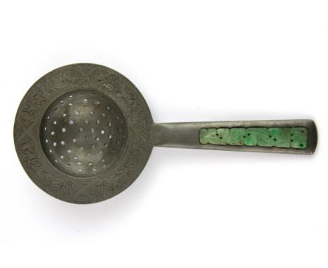 A 1920's Chinese engraved pewter tea strainer, the handle inset with carved jade, L. 18cm.