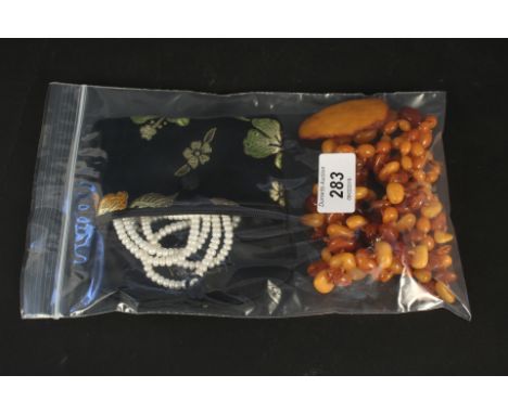 Two strings of amber coloured beads, an amber brooch plus a pearl necklace