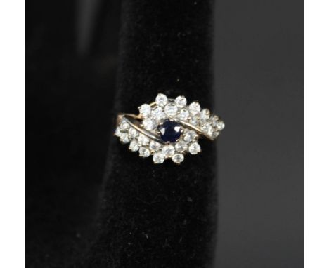 A 9ct gold ring set with central sapphire and white stone cluster border, size T