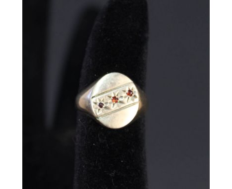 A 9ct gold signet ring set with three small garnets, size L