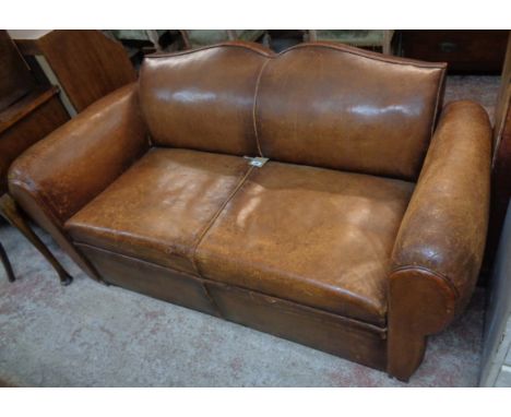 A 5' 5" 1930's  French brown leather upholstered two seater moustache back club sofa with roll-over arm rests, set on block f