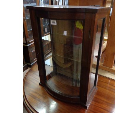 An 18" mahogany break bow front collector's cabinet with two glass shelves, glazed sides and door