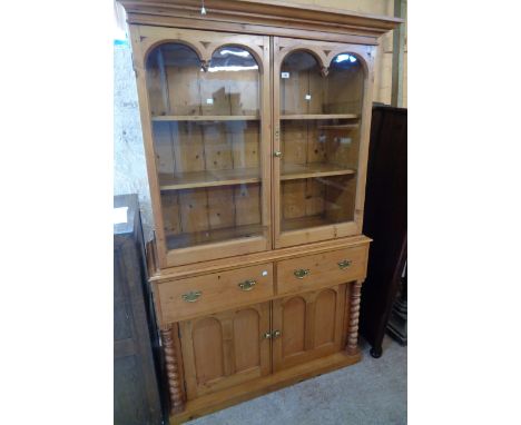 A 48 1/2" Victorian waxed pine two part dresser with moulded cornice and Gothic style detailing to glazed top, over a base wi