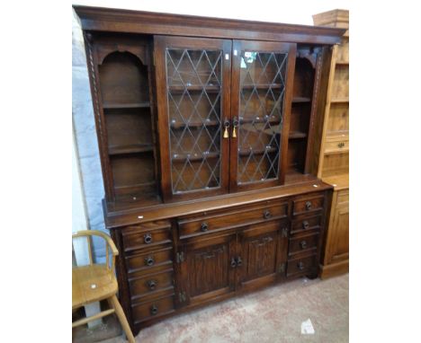 A 5' 1" Jaycee stained oak two part cabinet, the break front top section with pair of leaded glazed panel doors and flanking 