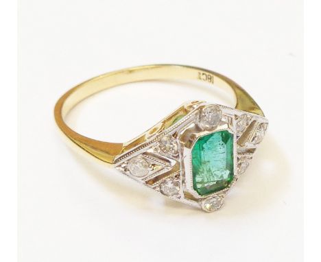 A marked 18ct. yellow metal ring, set with central emerald within a diamond encrusted pierced border