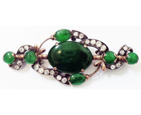 A marked 18k rose metal framed brooch, set with large central dark green jade oval panel within an open meandering border set