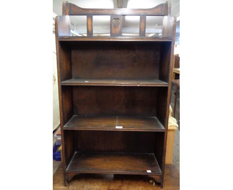 A 24" early 20th Century stained oak four shelf open bookcase with heart pierced raised back, set on bracketed standard ends