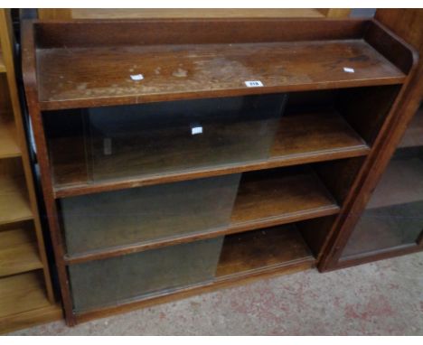 A 36" oak three shelf bookcase enclosed by three pairs of glass sliding doors