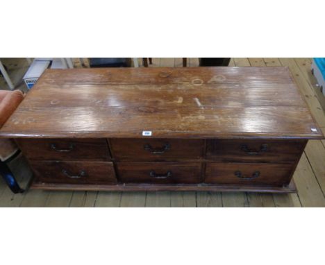 A 4' 10" Indian hardwood Pasha chest with moulded top and opposing banks of six short drawers, set on bracket feet