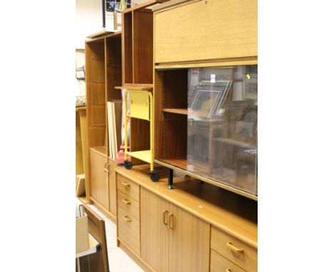 A teak sideboard with two cupboard doors flanked by three drawers, a teak display unit with sliding glass doors enclosing she