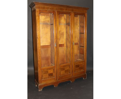An Edwardian mahogany and satinwood strung three section bookcase, the moulded cornice above an inlaid frieze and three part 