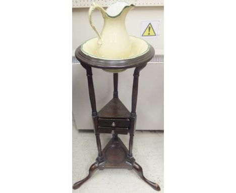 A mahogany circular wash stand with miniature pottery jug and bowl, over two drawers and a pot shelf, on cabriole tripod base