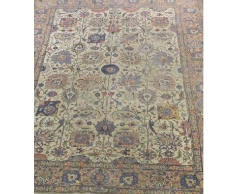 A Tabriz carpet with all-over foliate decoration in reds, blues and pinks on a cream ground, within a three margin border, th