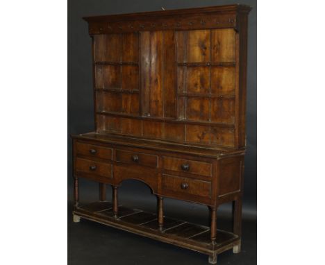 An early 19th Century oak dresser, the boarded plate rack with central recess flanked by three open shelves over a long lower