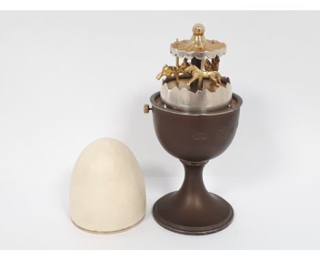 Anthony Elson Limited Edition silver gilt and enamel surprise egg in an egg cup, London 1980, the white enamel egg lifting to