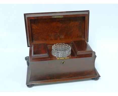 Early 19th century flame mahogany tea caddy of sarcophagus form, with fitted interior and twin ring handles, raised on bun fe