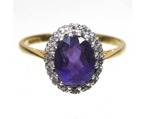 An 18 carat gold amethyst and diamond cluster ring, with a central oval facet cut stone, within a diamond surround, 3.5g, siz