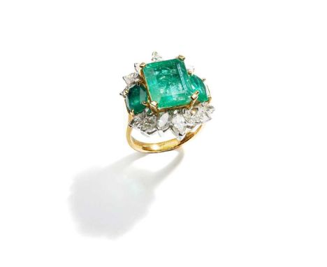 The cut-cornered step-cut emerald between oval-cut emerald shoulders, to a marquise-cut diamond frame, mounted in 18ct gold, 