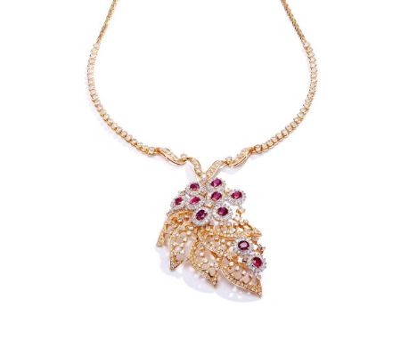 The pendant composed of oval-cut ruby and brilliant-cut diamond clusters, to a stylised foliate spray set with circular and s