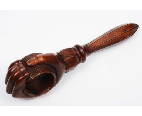 A TREEN CARVED WOODEN NUTCRACKER in the form of clenched fist, holding a walnut 19cm long 