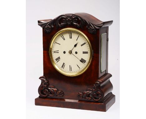 A 19TH CENTURY MAHOGANY MANTEL CLOCK with arched top, the case with foliate and scroll carved decoration, having white enamel