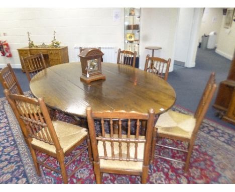 A REPRODUCTION GEORGIAN STYLE OAK WAKE TABLE, with two rounded drop leaves to form an oval supported by four pivoting gate le