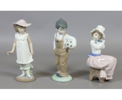 Three Nao porcelain figures; one of a girl seated holding a puppy, one of a boy holding a football and one of a girl in dress