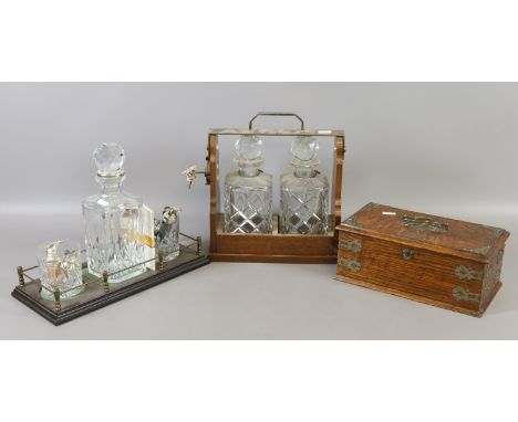 Three items; a oak two bottle tantalus with cut glass decanters having silver decanter labels, assayed Birmingham 1970, an oa