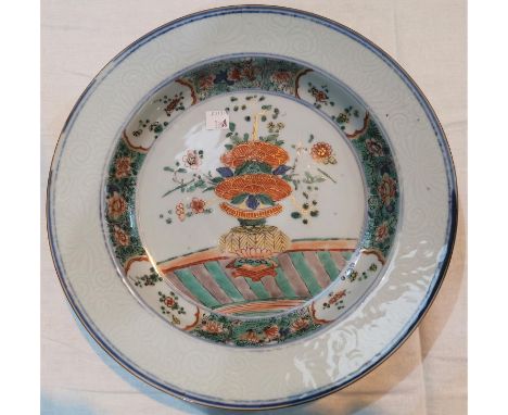 An 18th century Chinese porcelain shallow dish with relief underglaze scroll border, central decoration in the famille verte 