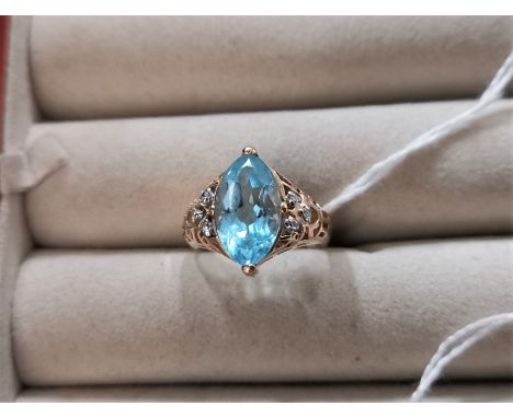 A 9 carat gold dress ring set marquise cut pale blue stone flanked by 6 small diamonds 