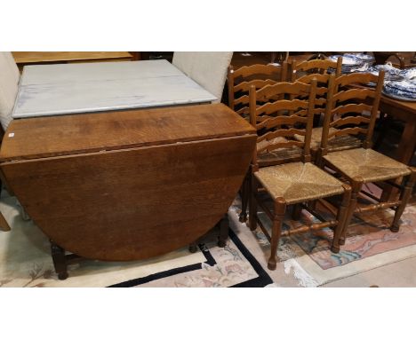 A golden oak heavy drop leaf dining table with oval top, on turned legs, and 4 oak chairs with ladder backs and rush seats 