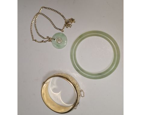 An oriental jade coloured hardstone pendant on curb chain, stamped '9Kt', 4.4 gm; a similar bangle; a gold plated bangle 