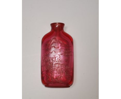 A Chinese ruby coloured glass snuff bottle engraved with landscapes to one side, 28 character text to the other, impressed se