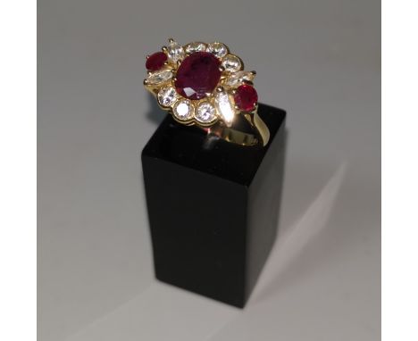 An 18 carat hallmarked gold ruby and diamond dress ring, set oval central ruby and 2 rubies either side, the border formed fr