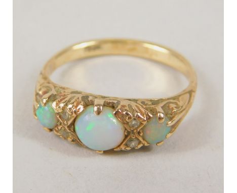 A 9ct gold dress ring, set with three opals, and four tiny white stones, with floral scroll shoulders, 2.9 grams all in