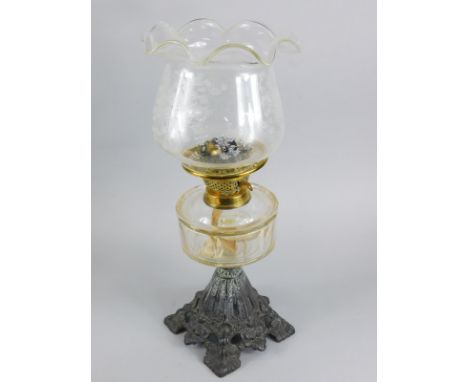 An early 20thC and later cast metal brass and clear glass oil lamp, with floral shade etched with flowers, above a clear rese