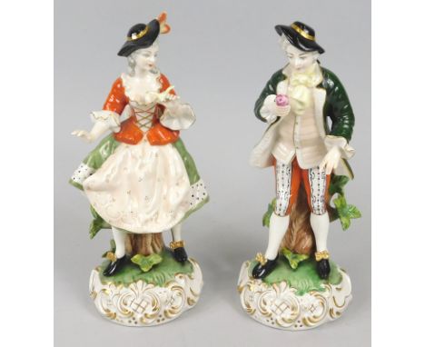 A pair of Kunst ceramic figures, each decorated in the form of a lady and gentleman, wearing 18thC dress on a roccoco scroll 