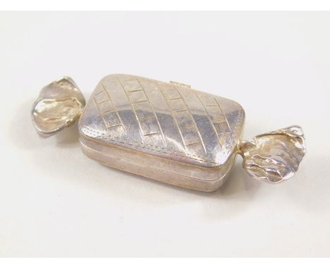 An early 20thC miniature casket, in the form of a sweet, with twist ends and engine turned centre, with removable lid, white 