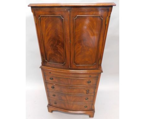 A mahogany finish bow front cabinet, the upper section with an over hanging top with a wide cross banding with two fielded pa