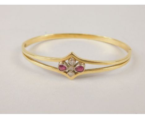 A hinged bangle, with two row floral design centred with ruby and diamond flowers, yellow metal, marked 750, 6.5cm dia