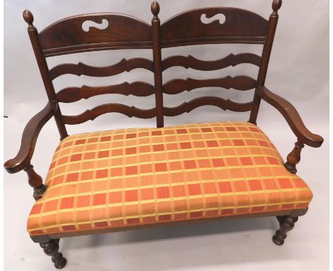 An unusual late 19th/early 20thC mahogany chair back sofa, with three turned finials, pierced rail, shaped ladders, on padded